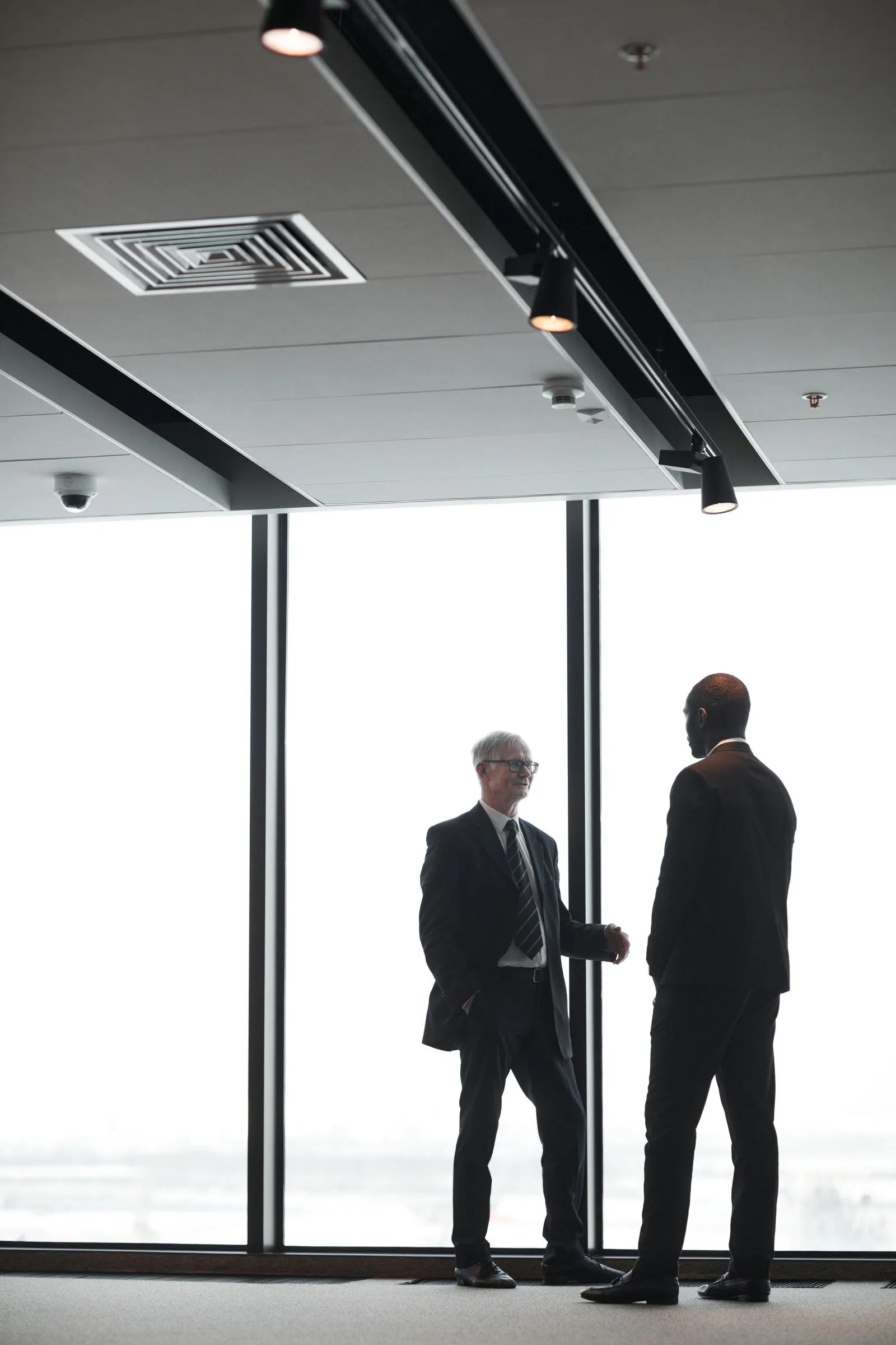 Two partners of the firm in conversation by a window